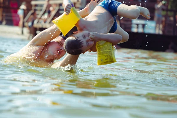 Father throwing son in water having fun — Stock Photo, Image