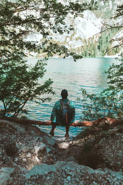 Muž s batohu na dřevu, který si vychutnával výhled na vodu — Stock fotografie