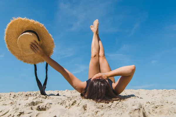 Женщина лежит на песчаном пляже скрещивая ноги отпуск — стоковое фото