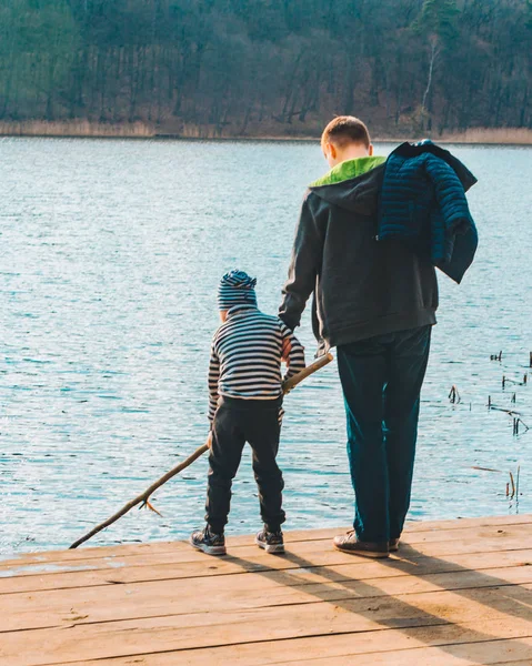 Père avec garçon enfant jouer avec banc près de l'eau — Photo