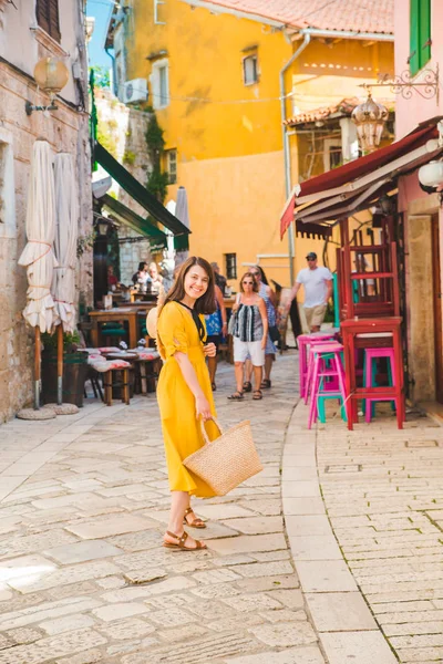 Туристическая женщина в желтом сарафане прогулка по маленькой хорватской улице города — стоковое фото