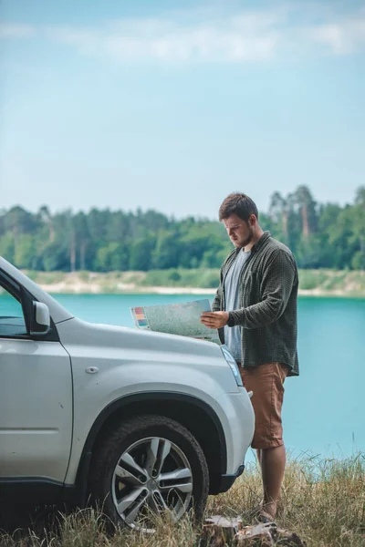 Homem do conceito do curso de carro que olha no homem no lago da capa do carro do SUV no fundo — Fotografia de Stock