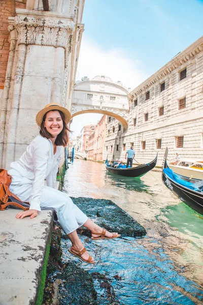 Mulher sentada no cais da cidade em Veneza itália apreciando a vista dos canais com gôndolas — Fotografia de Stock