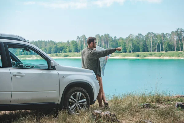 Homem do conceito do curso de carro que olha no homem no lago da capa do carro do SUV no fundo — Fotografia de Stock