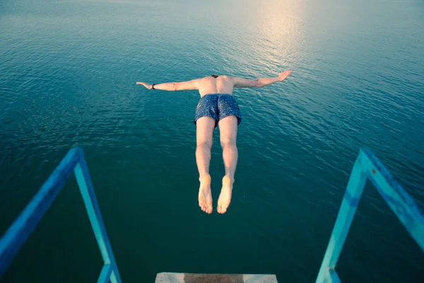 Uomo che salta dalla torre all'acqua del lago al tramonto — Foto Stock