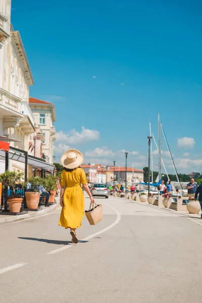 Žena ve žlutém slunci chůze po letovisku letní město — Stock fotografie