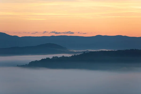 Vista do nascer do sol sobre a névoa das montanhas e nuvens sob picos — Fotografia de Stock