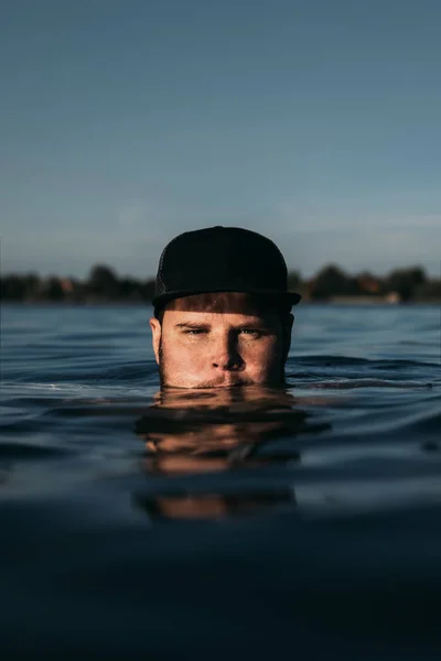 Úszás férfi fekete sapka portré vízben naplemente idő — Stock Fotó