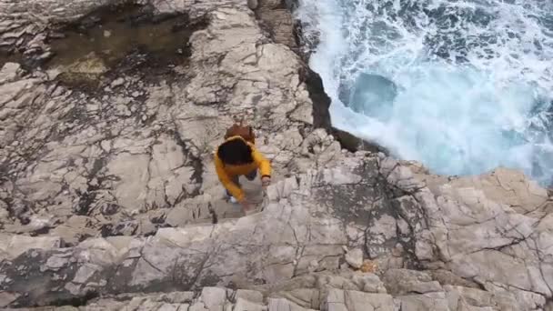 Kvinna Gul Regnrock Klättring Rocky Cliff Nära Seaside Stormiga Väder — Stockvideo