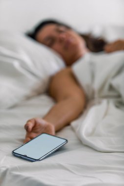 elinde yatakta telefon uyuyan kadın