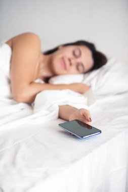 elinde yatakta telefon uyuyan kadın