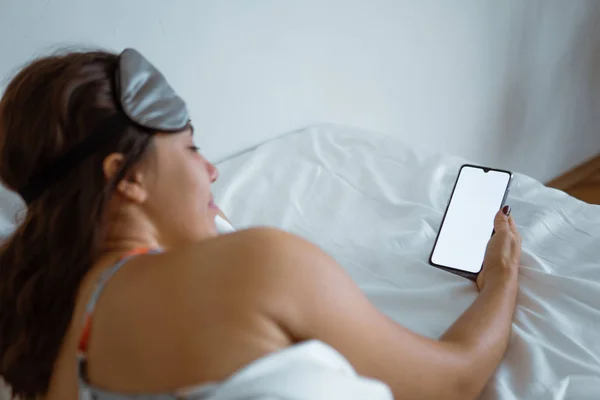 Woman awake looking into smartphone white screen — Stock Photo, Image