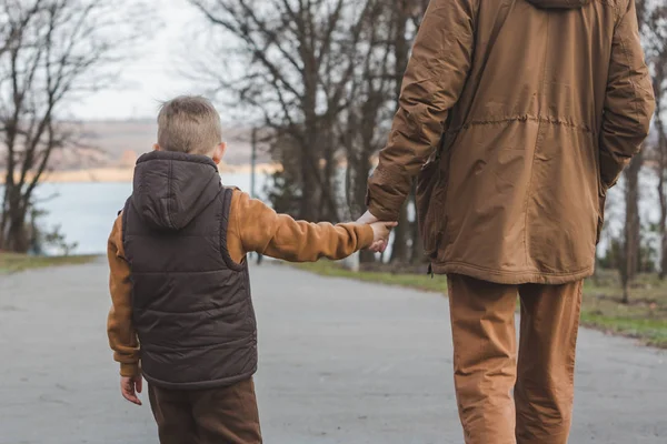 Ojciec z synem chodzenie przez Park trzymając ręce — Zdjęcie stockowe