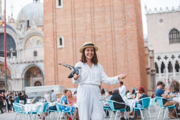 Woman in white clothes with straw hat having fun with pigeons at venice city square — Stock Photo, Image