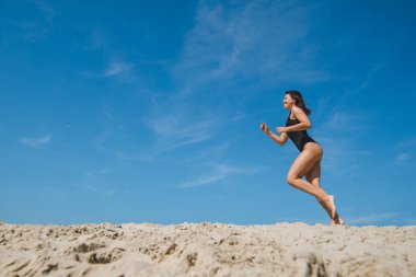 arka planda siyah mayo mavi gökyüzü kum plajda kadın