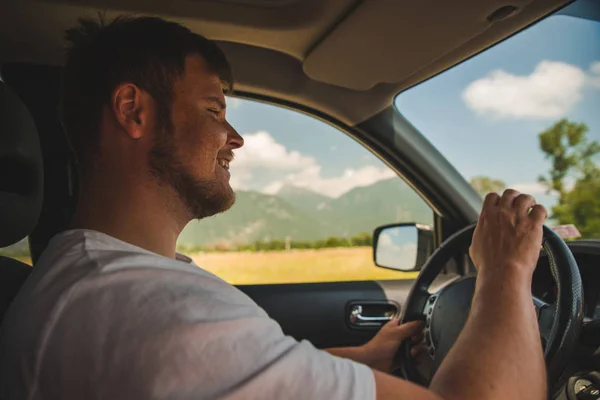Homem dirigindo carro olhando para montanhas — Fotografia de Stock