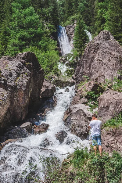 Man voor waterval in bergen bos — Stockfoto