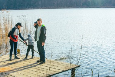 su kenarında bankla oynayan erkek çocuklu baba ve anne