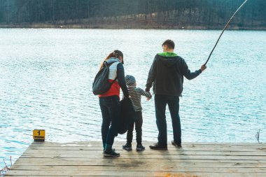 su kenarında bankla oynayan erkek çocuklu baba ve anne