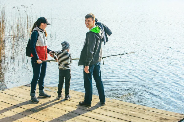 Padre y madre con niño jugando con el banco cerca del agua —  Fotos de Stock