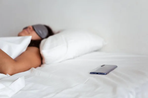 Woman sleeping in sleep mask smartphone near her — Stock Photo, Image