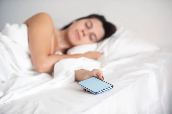 Жінка спить в ліжку телефон в руці — стокове фото