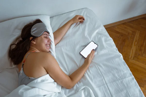 Жінка прокинулася, дивлячись на білий екран смартфона — стокове фото