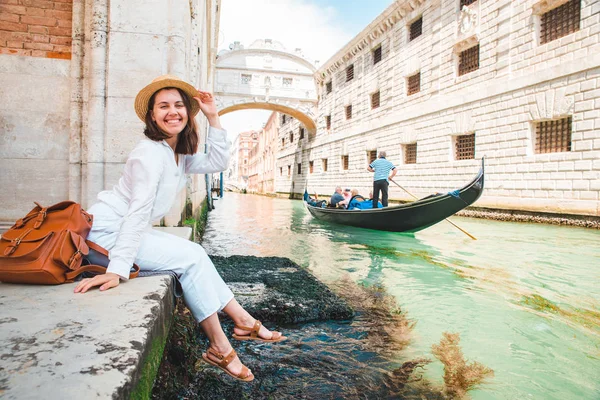 Mulher sentada no cais da cidade em Veneza itália apreciando a vista dos canais com gôndolas — Fotografia de Stock