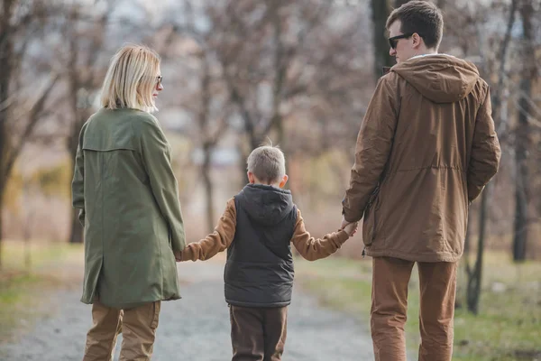 Молода красива сімейна прогулянка тримає руки біля міського парку — стокове фото