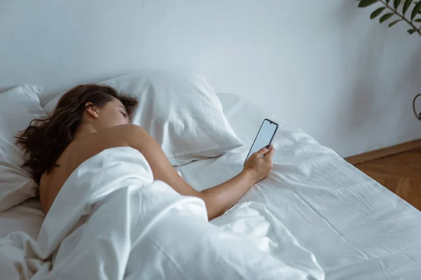 Woman awake looking into smartphone white screen — Stock Photo, Image