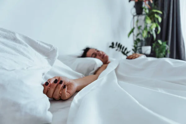 Kvinna sova i sängen hand nära upp selektiv fokus — Stockfoto