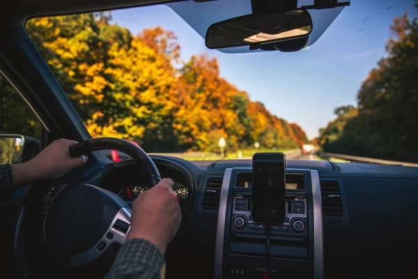 Man hands on steering wheel riding by autumn speedway fall season — Stock Photo, Image