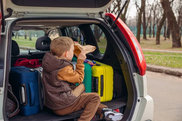 Mały dzieciak patrząc w papierową torbę z cukierkami siedzi w bagażniku samochodu — Zdjęcie stockowe