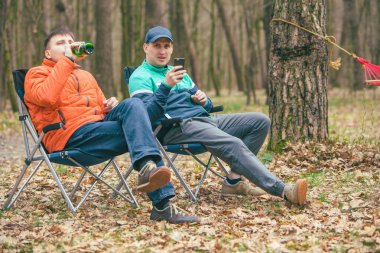 adam arkadaşlar sandalyede oturan içme ayı konuşuyor. ormanda dinlenme