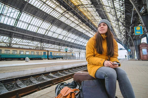 Young woman sit at railway station on her bags. Waiting for train. copy space — Stock Photo, Image