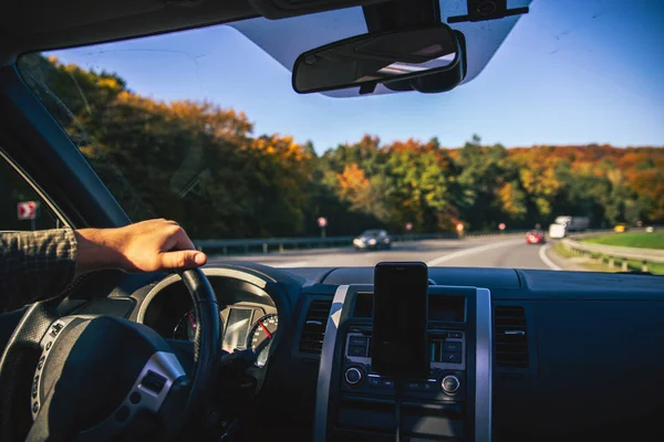 Man hands on steering wheel riding by autumn speedway fall season — Stock Photo, Image