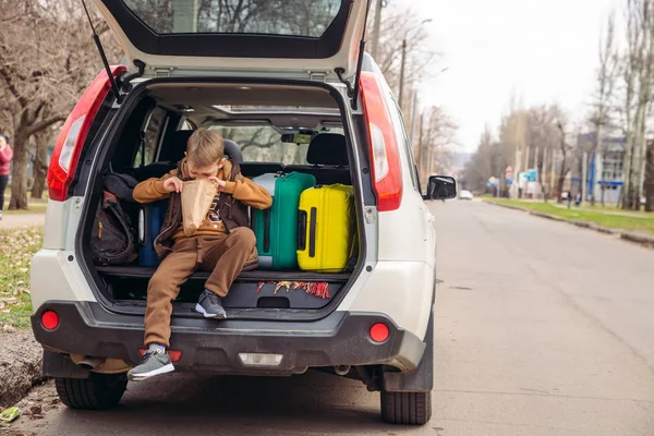 차 트렁크에 사탕이 들어 있는 종이 봉투를 보고 있는 꼬마 — 스톡 사진