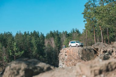 ormanda kayalık uçurumun kenarında oturan adam.