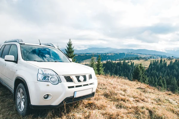 Branco suv carro no topo da colina montanhas no fundo — Fotografia de Stock