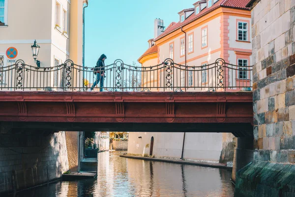 woman walking by bridge in autumn daytime by old european city