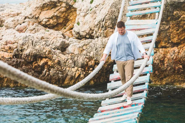 man walking by suspension bridge cross adriatic sea summer time