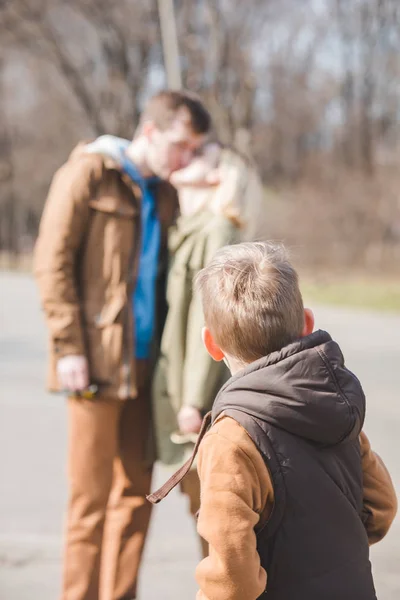 Glimlachend jongetje vooraan. zoenen ouders op achtergrond — Stockfoto