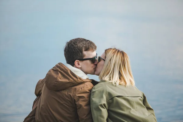Söt par kyssar vid Riverside sitter på marken — Stockfoto