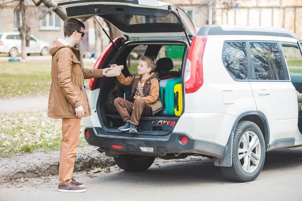 Батько з сином упаковки мішків для багажника автомобіля. концепція подорожей автомобілем — стокове фото