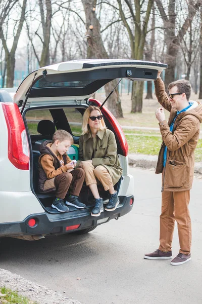 Молода сімейна упаковка для подорожей автомобілем. покласти мішки в багажник — стокове фото