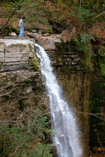 Человек на краю, глядя на водопад туристической концепции — стоковое фото