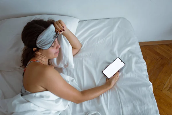 Жінка спить у сні маска смартфон поруч з нею — стокове фото