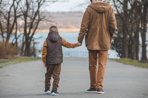 Padre con hijo caminando por el parque tomados de la mano —  Fotos de Stock
