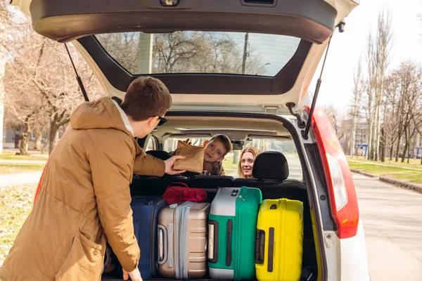 Família jovem pronta para viajar de carro. tronco cheio de bagagem — Fotografia de Stock