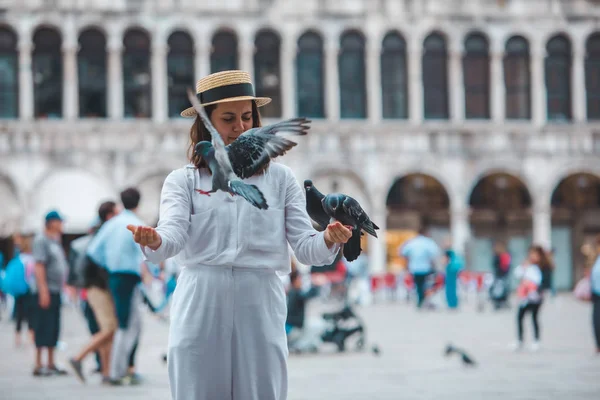 Žena v bílém oblečení se slamákem baví s holuby na náměstí Benátky — Stock fotografie